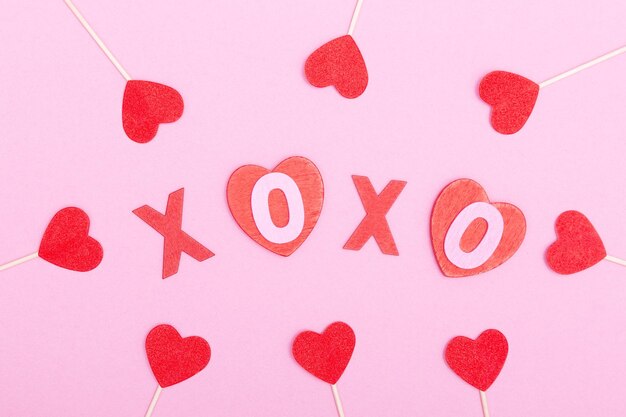 Die Inschrift xo xo aus Holzbuchstaben und Herzen auf rosafarbenem Hintergrund Das Konzept von Valentine39s Day Love Dating und Hochzeit Kuss Symbol flach lag Minimalismus