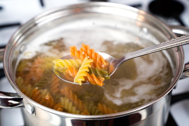 Foto die italienische dreifarbige fusilli-paste wird in einem topf auf dem herd gekocht, um pasta zu kochen.