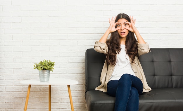 Die junge arabische Frau, die auf dem Sofa hält Augen sitzt, öffnete sich, um eine Erfolgschance zu finden.