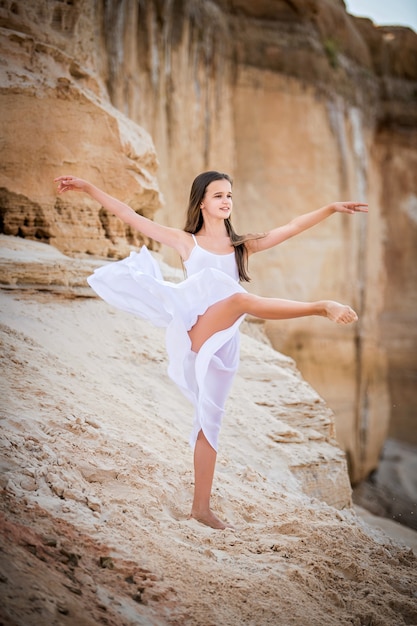 Die junge Ballerina steht in einer anmutigen Pose am Rand einer sandigen Klippe