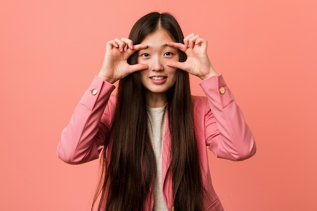 Die junge chinesische Frau des Geschäfts, die den rosa Anzug hält Augen trägt, öffnete sich, um eine Erfolgschance zu finden.