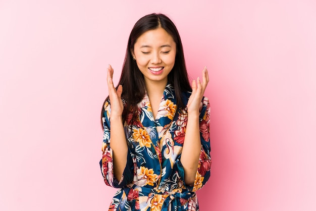 Die junge chinesische Frau, die einen Kimono-Pyjama trägt, lokalisierte frohes viel lachen. Glück-Konzept.