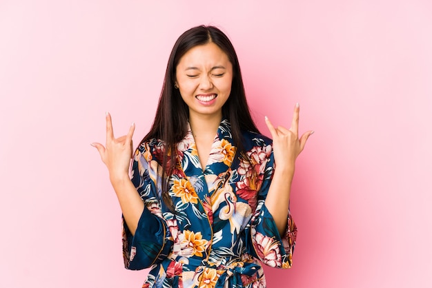 Die junge chinesische Frau, die einen Kimonopyjama trägt, lokalisierte das Zeigen der Felsengeste mit den Fingern