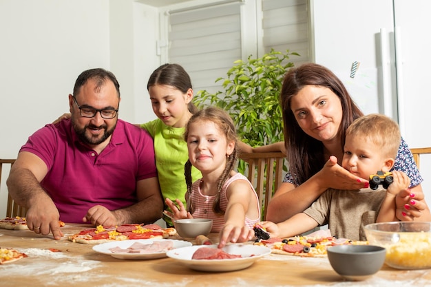 Die junge Familie bereitet zu Hause gemeinsam Pizza zu