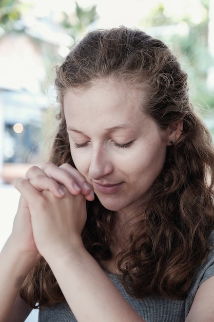 Die junge Frau, die mit Augen betet, schloss