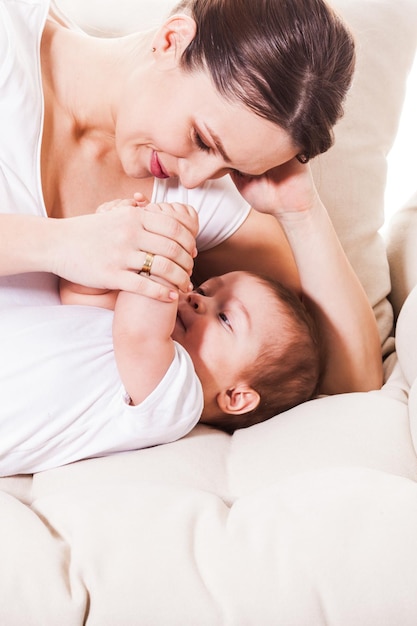 Die junge Frau liegt mit einem süßen Baby auf der Couch