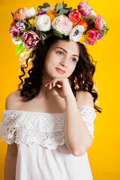 Die junge Frau mit einem Blumenkranz auf dem Kopf, der ihr Gesicht berührt, isoliert