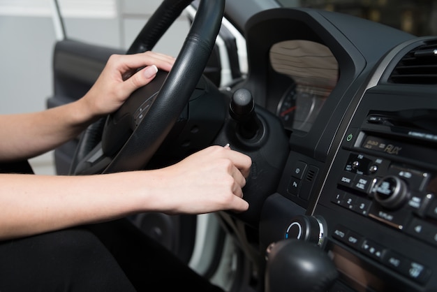 Die junge Frau startet das Auto.