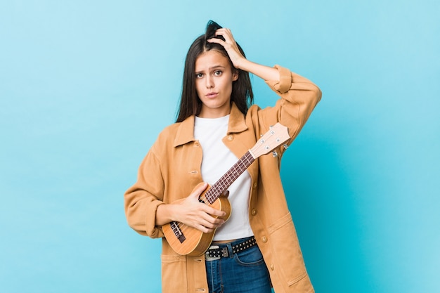 Die junge kaukasische Frau, die ein ukelele ist entsetzt anhält, hat sie sich an wichtige Sitzung erinnert.