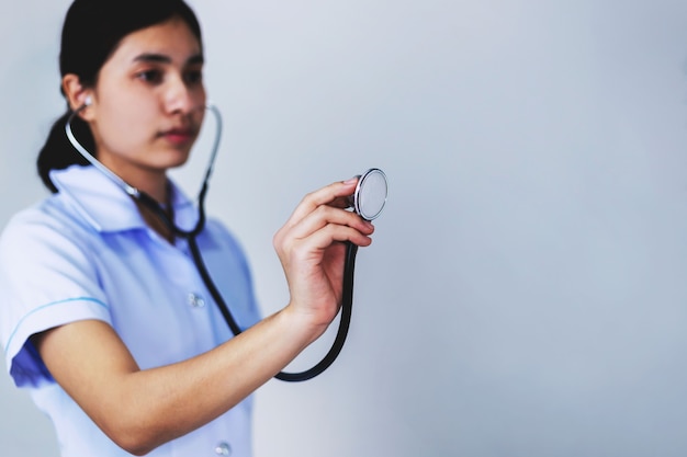 Die junge Krankenschwester hielt ein Stethoskop in der Hand, das sich nach vorne ausstreckte.