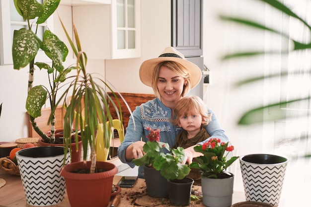 Die junge Mutter und ihr Sohn beschäftigen sich zu Hause mit dem Anbau von Blumen zu Hause