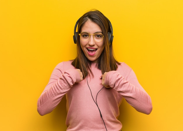 Die junge nette Frau, die überraschte Musik hört, fühlt sich erfolgreich und wohlhabend