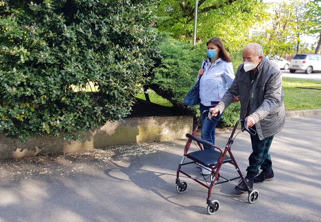 Die junge Pflegekraft begleitet einen älteren Herrn, der ihm hilft, im Park spazieren zu gehen