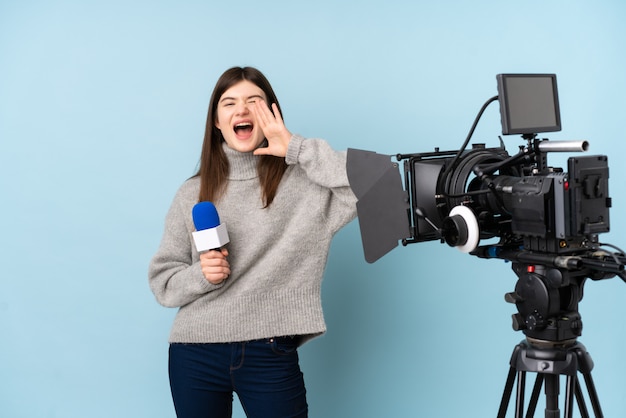 Die junge Reporterfrau, die ein Mikrofon hält und die Nachrichten schreit mit dem breiten Mund berichtet, öffnen sich