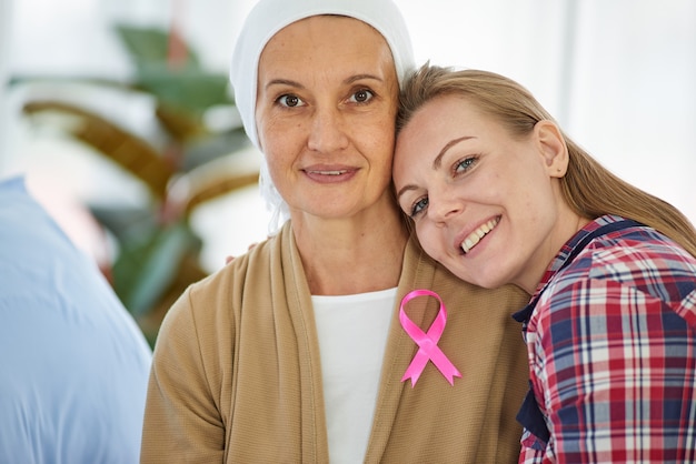 Die junge schöne Tochter sitzt neben der Mutter, die gegen den Krebs kämpft, um sie im Krankenhausbett zu unterstützen