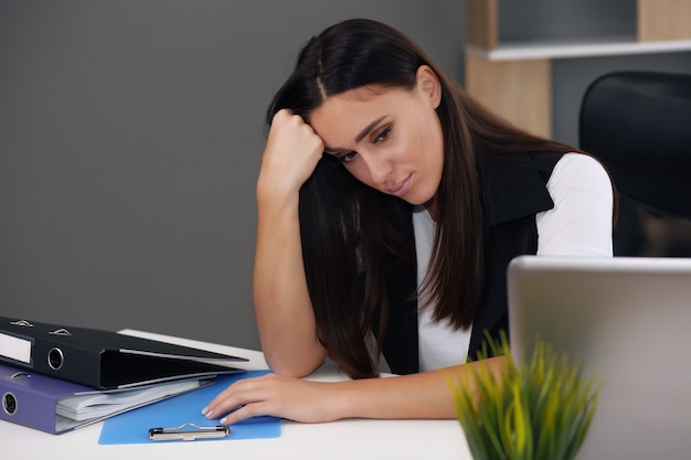 Die junge weibliche Inhaltsmanagerin einer Unternehmenswebsite überwacht die Abonnentenaktivität, während sie im Büro unter Verwendung eines Laptops arbeitet