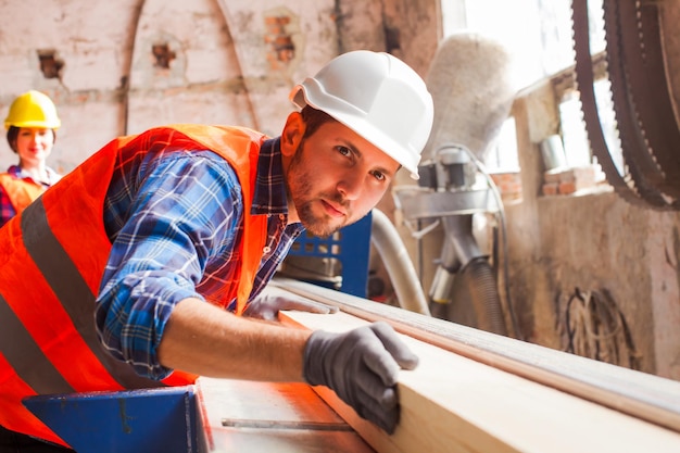 Die jungen Arbeiter schneiden Bretter in der Holzfabrik