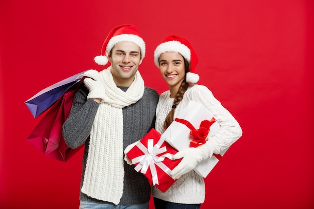 Die jungen attraktiven Paare, die Einkaufstasche halten, genießen, am Weihnachtstag zu kaufen und zu feiern.