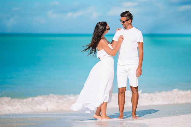 Die jungen Paare, die auf tropischen Strand mit weißem Sand- und Türkisozean gehen, wässern in Antigua-Insel in Karibischen Meeren