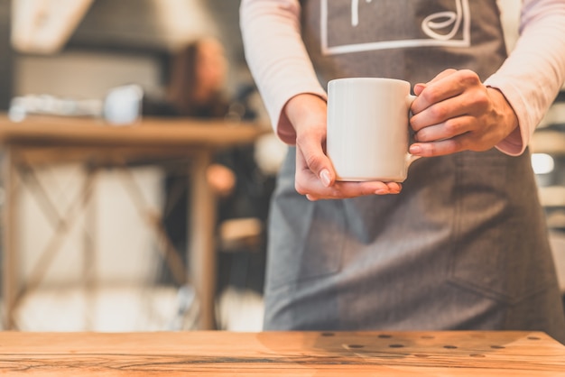 Die Kellnerin mit einer weißen Tasse in einem Café