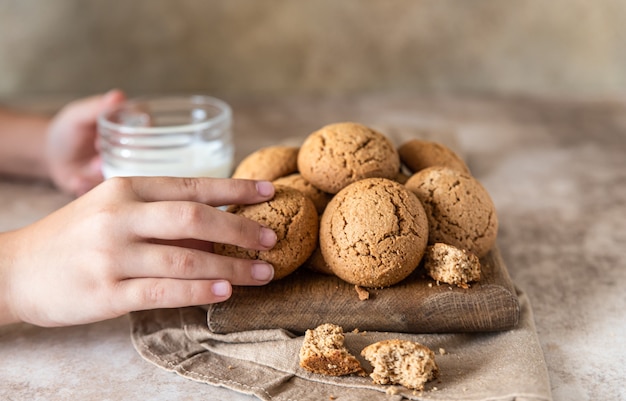 Die Kinderhand nimmt Haferkekse vom Brett Gesunder Snack oder Dessert