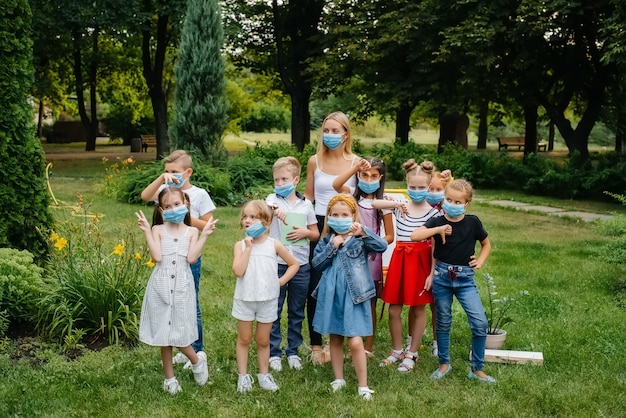 Die klasse der maskierten schulkinder trainiert während der epidemie im freien