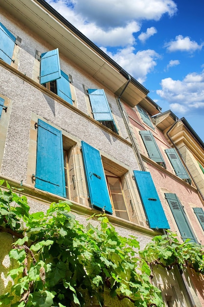 Die klassische Architektur eines hohen Wohnhauses mit überwucherten Grünpflanzen an der Wand Das Äußere eines alten Wohnblocks an einem sonnigen Tag Ansicht von unten auf antike Stadtwohnungen