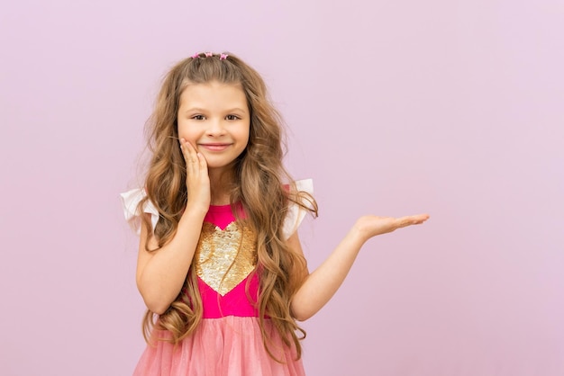 Die kleine Prinzessin zeigt auf die Anzeige. Ein Kind mit lockigem Haar. Lila isolierter Hintergrund.