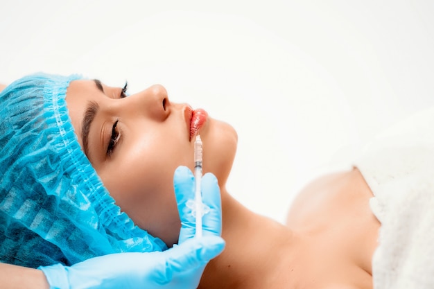 Die Kosmetikerin führt das Verfahren der verjüngenden Gesichtsspritzen durch, um die Falten auf der Gesichtshaut einer Frau in einem Schönheitssalon zu straffen und zu glätten. Kosmetik Hautpflege