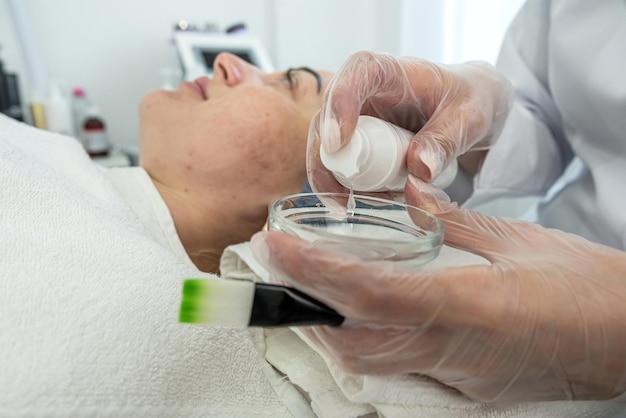 Die Kosmetikerin führt im Salon ein Kavitationsverfahren am Gesicht des Kunden durch