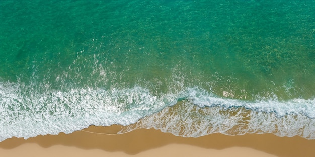 Die Kraft des Ozeans zeigt Wellen und trifft von oben auf den Sandstrand