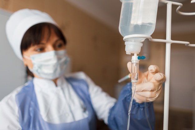 Die Krankenschwester in einer Krankenstation überprüft die Zählertropfen. Eine Ärztin kümmert sich nach der Operation um die Patientin. Das Konzept der Reinigung des Körpers