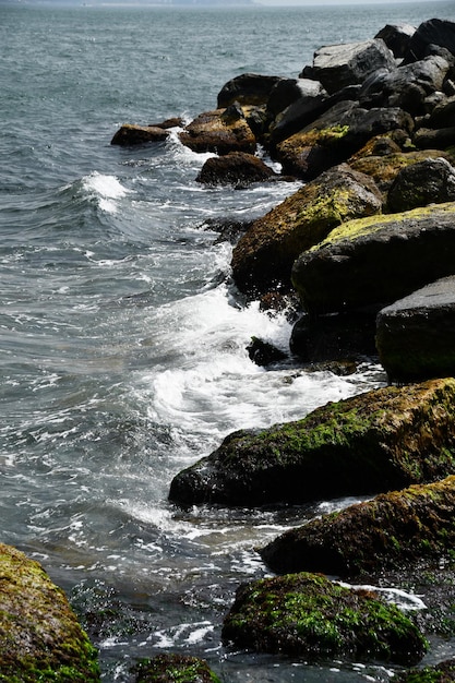 Die Küste der Meeresbucht mit großen Steinen Die Wellen stürzen auf die Felsen