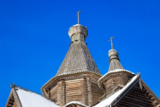 Die Kuppeln einer alten Holzkirche vor dem Hintergrund des klaren blauen Himmels Jahreszeit ist Winter