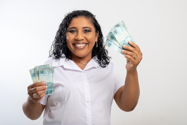 Die lächelnde Frau, die 100-Real-Noten in ihren Händen hält, zeigt auf das Geld in ihrer Hand. Brasilianisches Geld