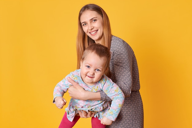 Die lächelnde positive junge Dame verbringt Zeit mit ihrem Kind