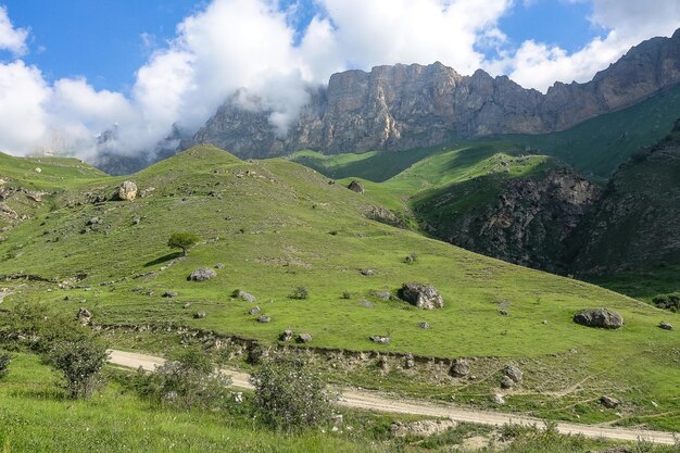 Die Landschaft des grünen Aktoprak Pass im Kaukasus die Straße und die Berge unter grauen Wolken KabardinoBalkarien Russland