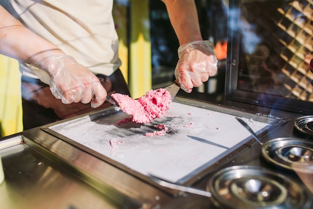 Die Leute, die angebratene Eiscreme machen, rollt an der Gefrierwanne.