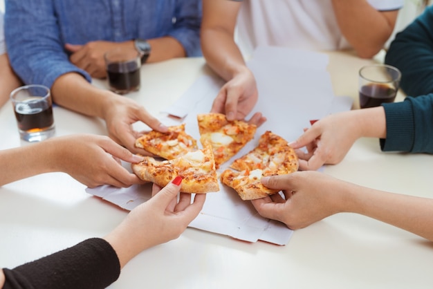 Die Leute essen Fastfood. Freundehände, die Pizzastücke nehmen