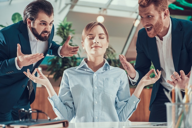 Die Leute schreien nach meditierenden Arbeiter in Anzug im Büro.