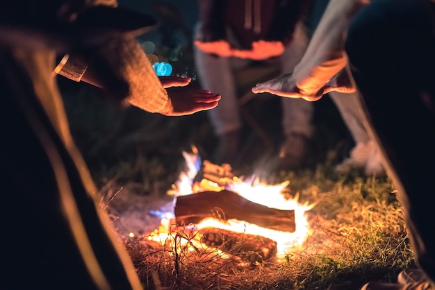 Die Leute wärmen sich die Hände in der Nähe des Lagerfeuers. Nachtzeit