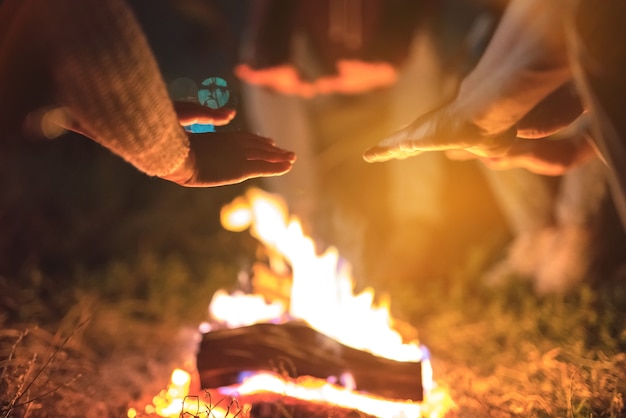 Die Leute wärmen sich die Hände in der Nähe eines Lagerfeuers. abend nacht zeit