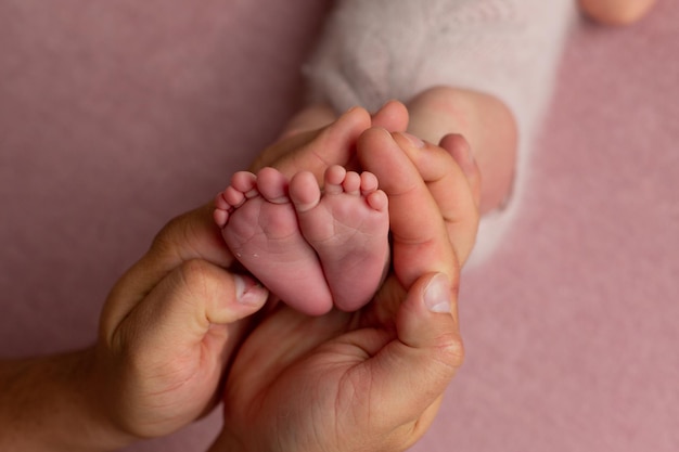 Die liebevolle Mutter hält die Beine eines kleinen Kindes in der Handfläche aus nächster Nähe. Das Glück der Frau.