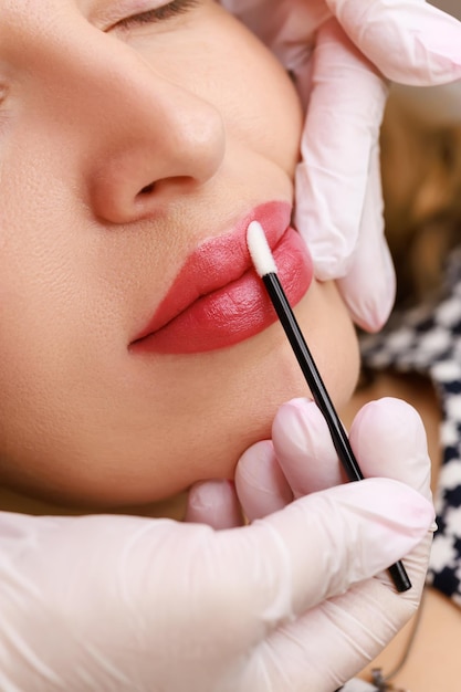 Die Lippen, auf denen Permanent Make-up gemacht wird, werden vom Meister mit einer Mikrobürste abgewischt, wodurch sie nach dem Tätowieren mit Feuchtigkeit versorgt werden