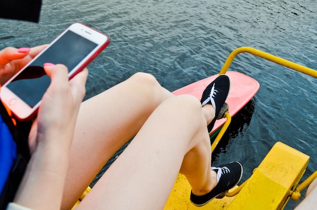 Die Mädchenfrau dreht ihre Füße auf den Pedalen einer Schwimmsportanlage eines Katamaranbootes