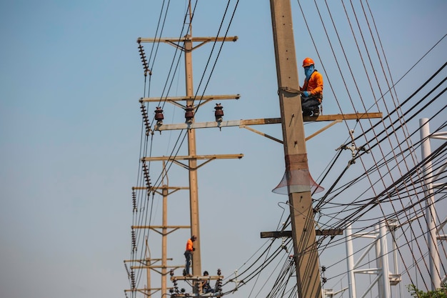Die männliche Arbeiterkran-Seilbahn repariert den Strommast und wächst um Stromleitungen herum.