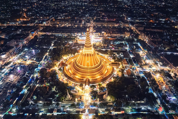 Die majestätische goldene Pagode von Phra Pathom Chedi leuchtet zwischen den Festivallichtern rund um den Kreisverkehr in der Innenstadt von Nakhon Pathom