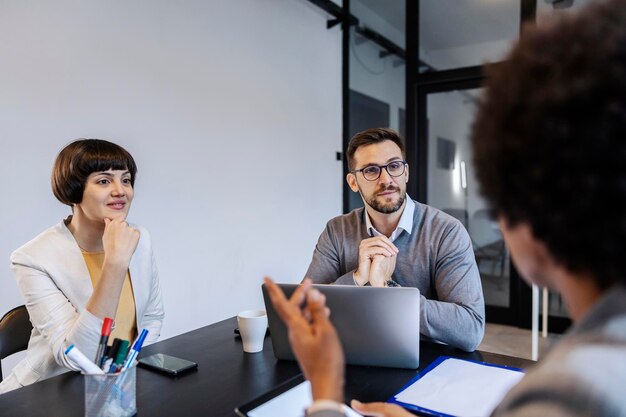 Die Manager sitzen im Sitzungssaal und hören einer Afrikanerin zu, die Ideen vorträgt