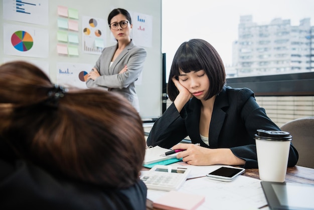 Die Managerin ist sauer auf zwei gelangweilte Geschäftsfrauen, die in einem Meeting schlafen, während sie die Präsentation hält