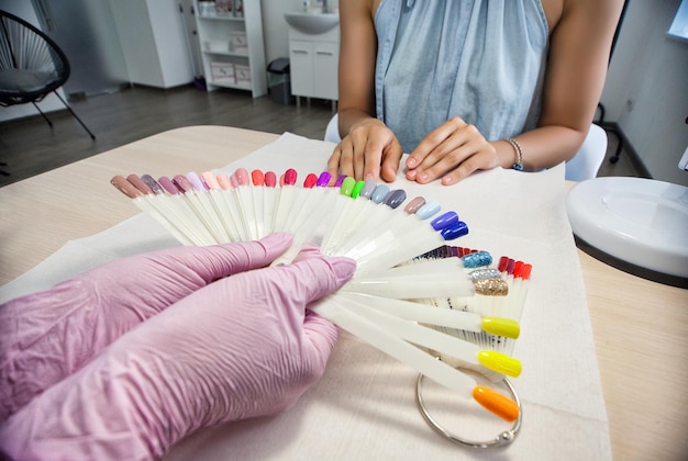 Die Maniküristin der Meisterin wählt mit den Fingern die Farbe des Nagellacks aus der Palette